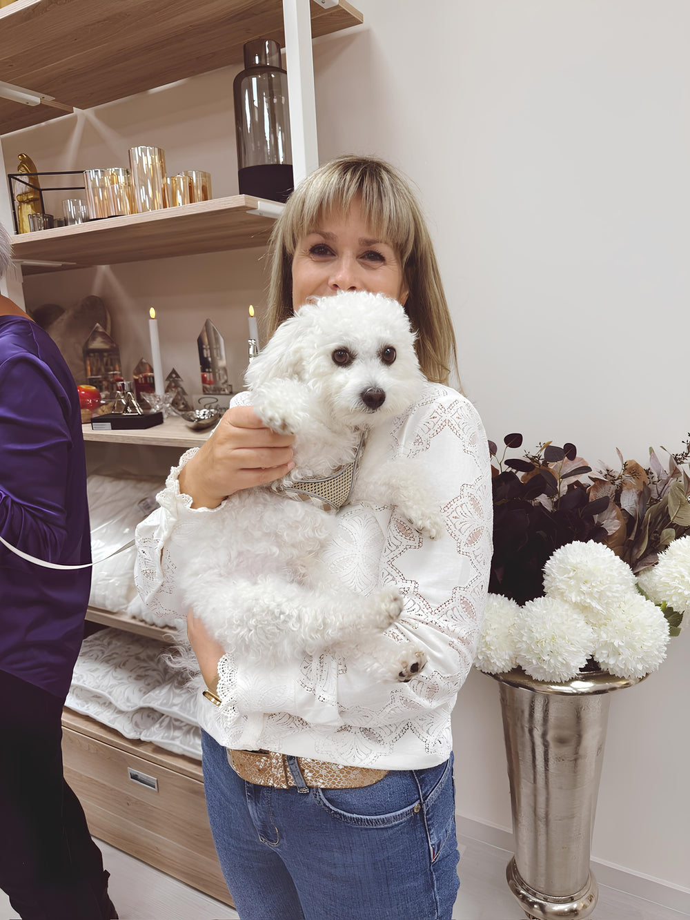 Geschäftsführerin von WohnSinn steht in ihrem Dekoladen und hält einen kleinen Hund im Arm.