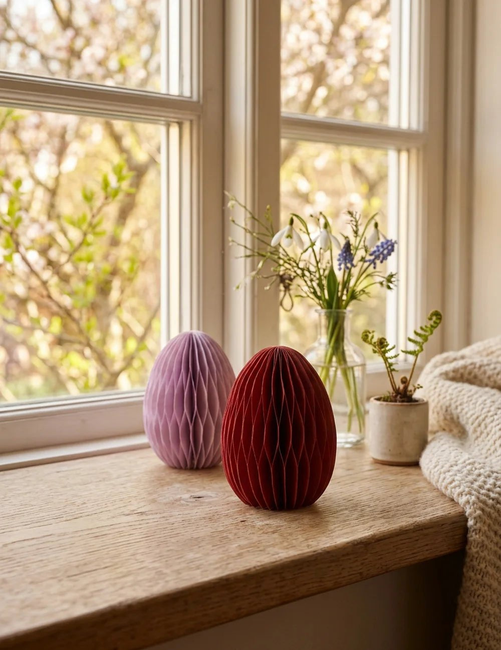 Papiereier Eggo auf sonniger Fensterbank mit Schneeglöckchen und Traubenhyazinthen in Glasvasen