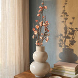 Pfirsichblütenzweig auf Holzkommode mit Blütenschatten an blaugrüner Wand