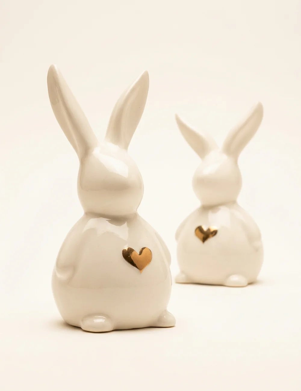 Zwei weiße Porzellan-Hasenfiguren Jeppe mit aufrechten Ohren und goldenem Herz auf der Brust