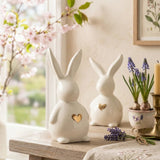 Zwei Jeppe-Hasen auf Holztisch mit Kirschblüten, Traubenhyazinthen und Messingkerzenhalter