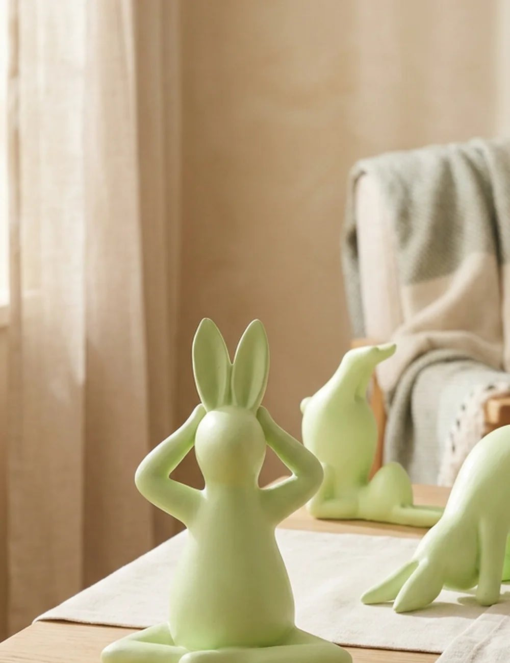 Meditierender Yoga-Hase frontal mit sitzender und sich verbeugender Figur im Hintergrund