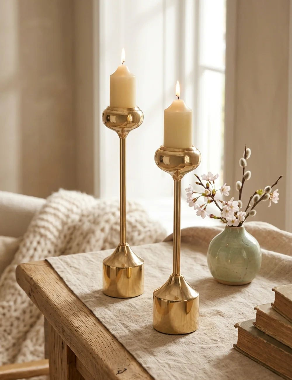 Goldene Kerzenleuchter Donus auf Holztisch neben Kirschblüten und Büchern