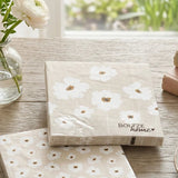 Zwei Servietten-Packungen Canea mit großem und kleinem Blumenmuster neben weißen Ranunkeln