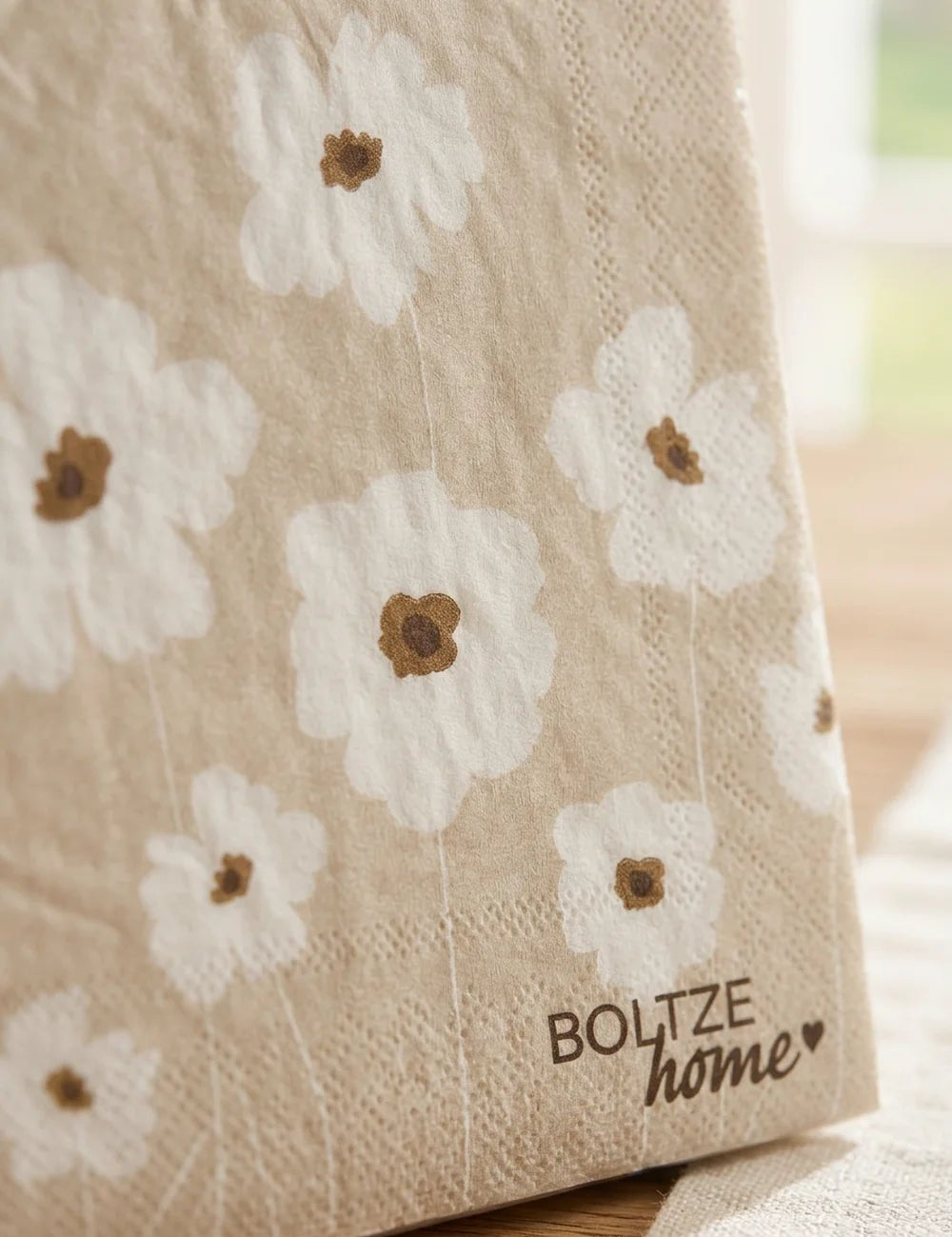 Einzelne Serviette Canea aufgestellt mit Gänseblümchen-Muster in Beige und Boltze-Logo
