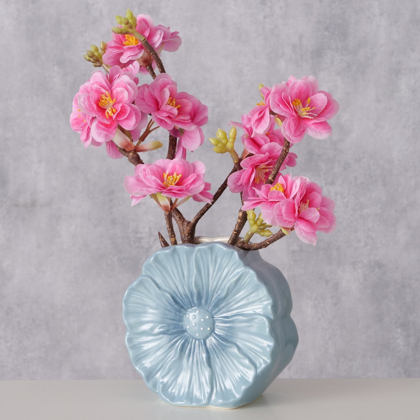Keramikvase Melany hellblau mit rosa Blütenzweigen vor grauem Hintergrund